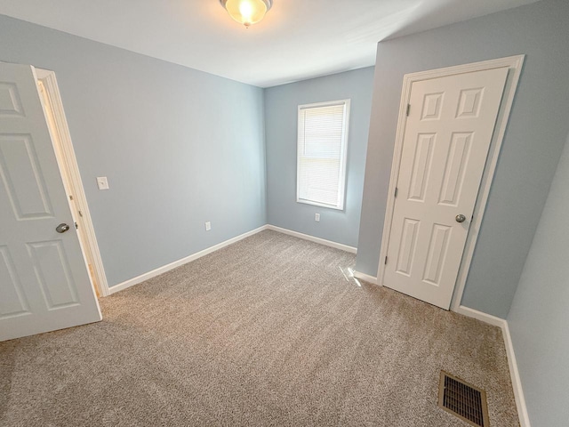 carpeted spare room featuring visible vents and baseboards