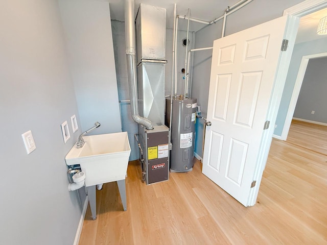 utility room featuring water heater and a sink
