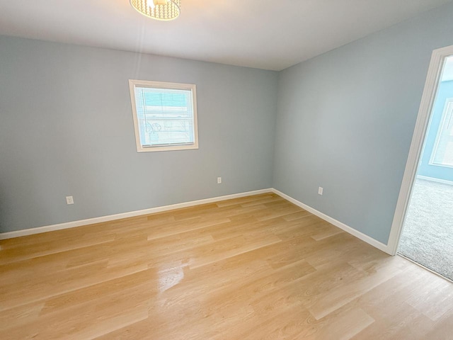 spare room featuring a wealth of natural light, light wood finished floors, and baseboards