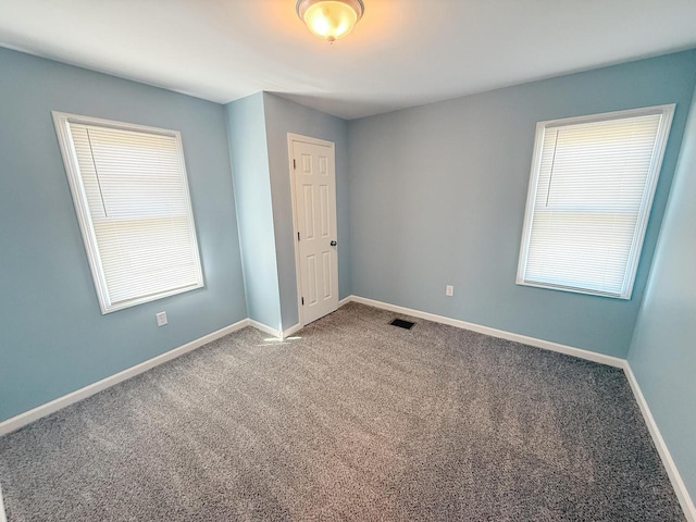 carpeted spare room with visible vents and baseboards
