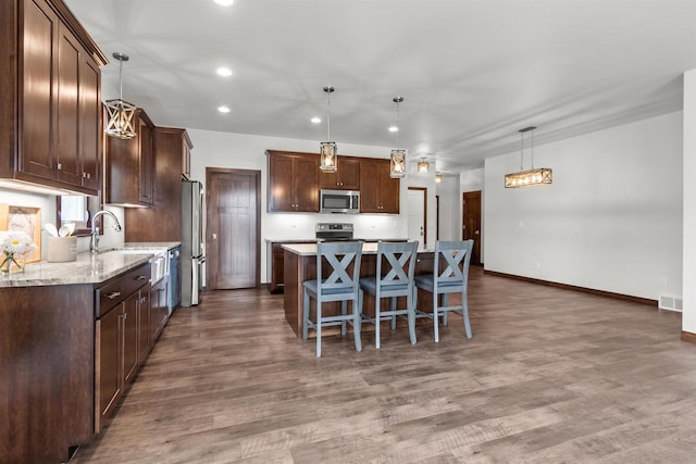 5096 N Milkweed Trl, Appleton, WI 54913 - kitchen with a kitchen bar, visible vents, a center island, wood finished floors, and stainless steel appliances