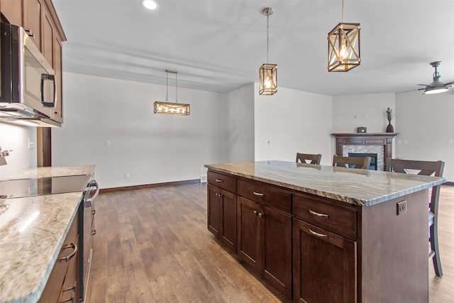 5096 N Milkweed Trl, Appleton, WI 54913 - kitchen featuring a kitchen breakfast bar, a fireplace, wood finished floors, stainless steel appliances, and hanging light fixtures