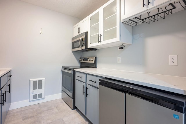 kitchen featuring light stone countertops, glass insert cabinets, visible vents, and stainless steel appliances