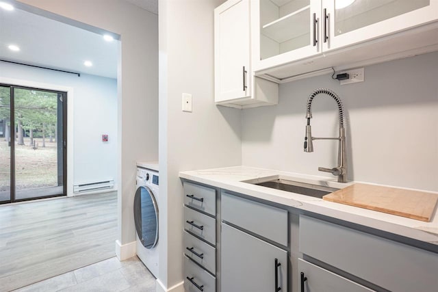laundry room featuring baseboard heating, recessed lighting, washer / dryer, cabinet space, and a sink