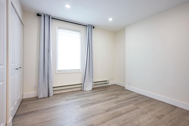 empty room with light wood-style flooring, recessed lighting, a baseboard heating unit, and baseboards