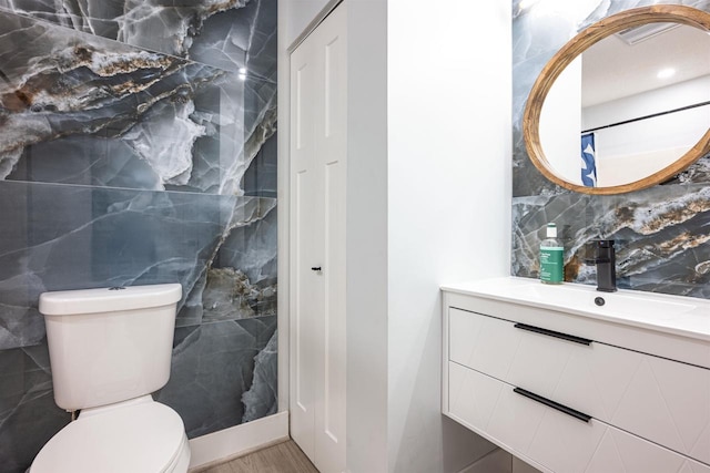 bathroom with vanity, tile walls, toilet, and wood finished floors