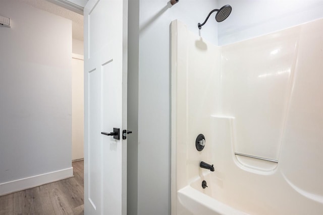 bathroom featuring baseboards, bathtub / shower combination, and wood finished floors