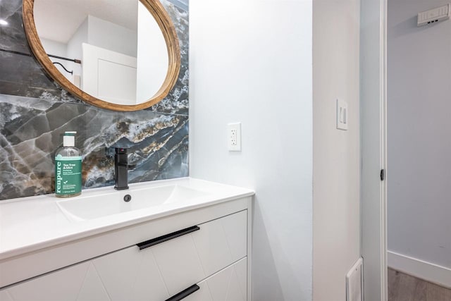 bathroom with vanity, visible vents, backsplash, and wood finished floors