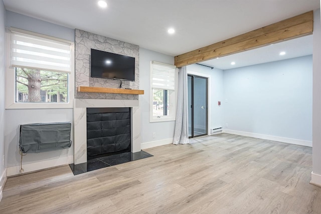 unfurnished living room featuring plenty of natural light, a large fireplace, and wood finished floors