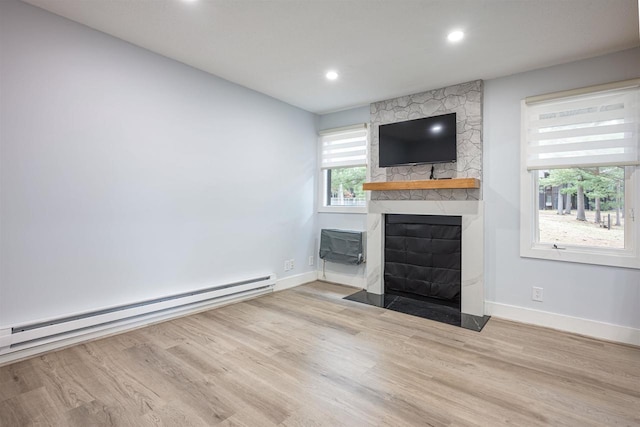 unfurnished living room with a stone fireplace, recessed lighting, baseboard heating, wood finished floors, and baseboards