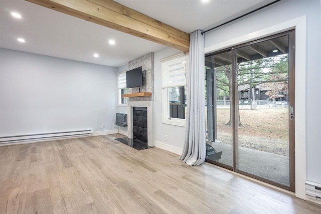 unfurnished living room with wood finished floors, a baseboard heating unit, a wealth of natural light, and recessed lighting