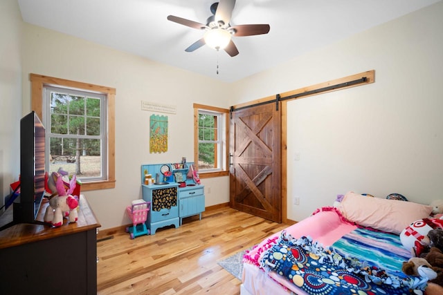 1979 9th Ave, Friendship, WI 53934 - bedroom with a barn door, ceiling fan, light wood-style flooring, and baseboards