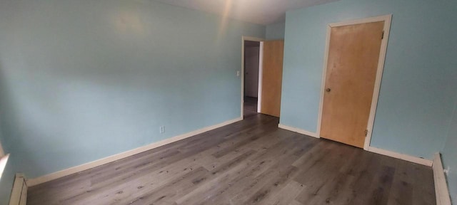 140 E Ave, Iron Ridge, WI 53035 - unfurnished bedroom featuring baseboards, a baseboard heating unit, and wood finished floors