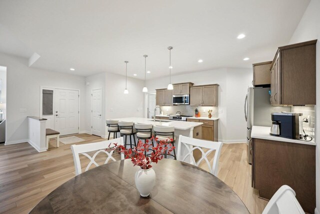dining space featuring baseboards, light wood finished floors, and recessed lighting