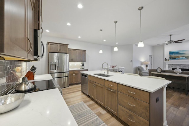kitchen with a sink, decorative backsplash, light wood-style flooring, and stainless steel appliances