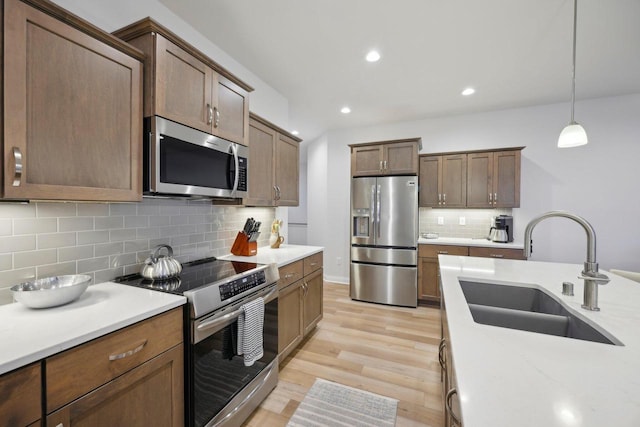 kitchen featuring tasteful backsplash, a sink, light wood-type flooring, recessed lighting, and stainless steel appliances