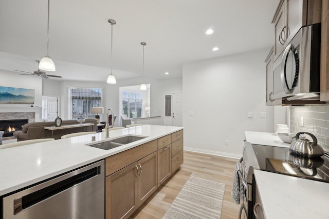 kitchen featuring stainless steel appliances, light countertops, a sink, and hanging light fixtures