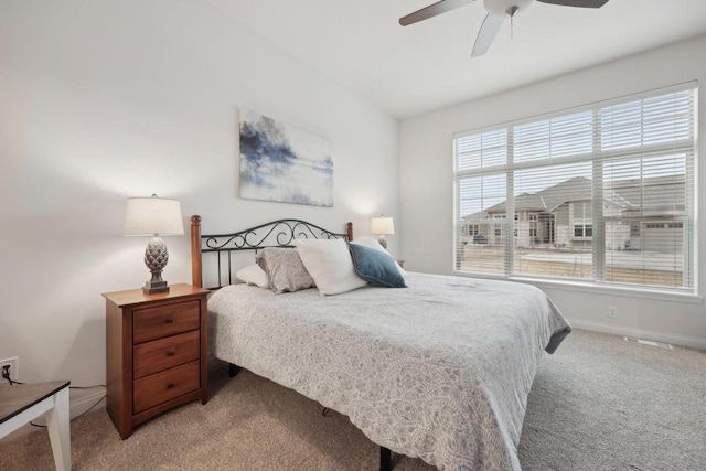 bedroom with multiple windows, light colored carpet, baseboards, and a ceiling fan