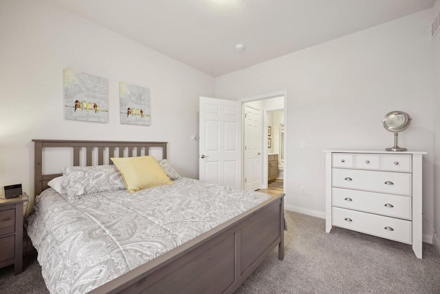 carpeted bedroom with visible vents, baseboards, and connected bathroom