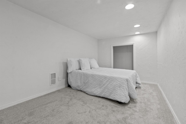carpeted bedroom with a textured wall, recessed lighting, visible vents, and baseboards