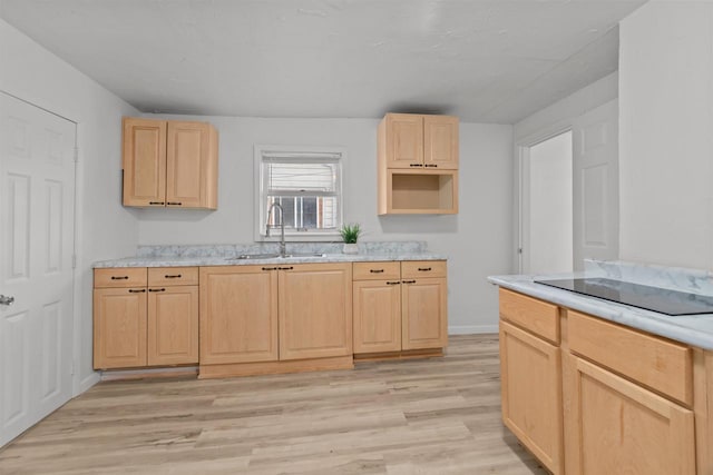 kitchen with light brown cabinetry, black electric stovetop, light wood finished floors, and a sink
