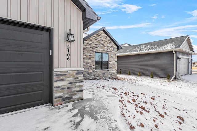 3106 Lazy Oak Dr, Green Bay, WI 54311 - snow covered property entrance with board and batten siding, stone siding, and a garage