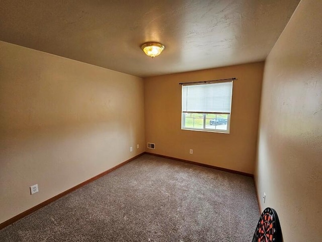 carpeted spare room featuring baseboards and visible vents