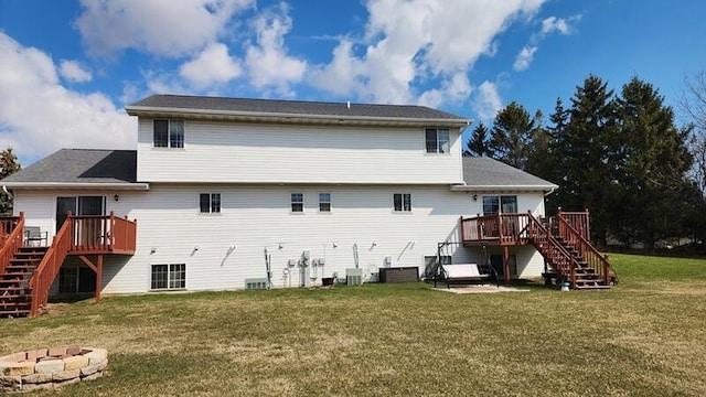rear view of house featuring an outdoor fire pit, a lawn, a wooden deck, and stairway