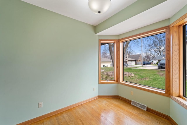 spare room with visible vents, baseboards, and wood finished floors