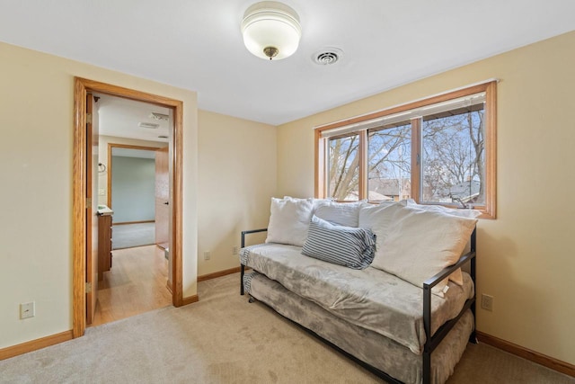 living area with visible vents, baseboards, and light carpet