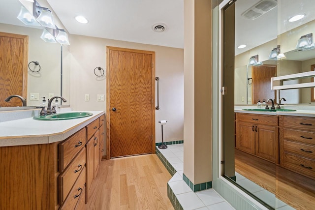 full bath featuring two vanities, visible vents, and a sink