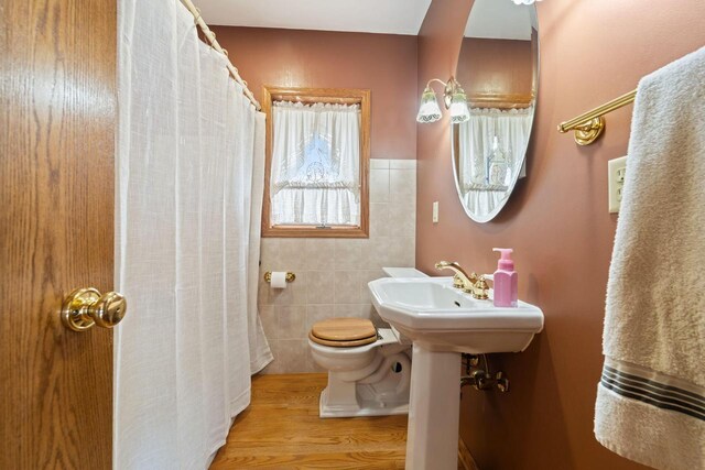 bathroom featuring tile walls, a shower with curtain, toilet, and wood finished floors