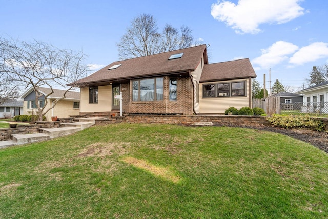 view of front of house featuring brick siding, a front lawn, fence, and a shingled roof