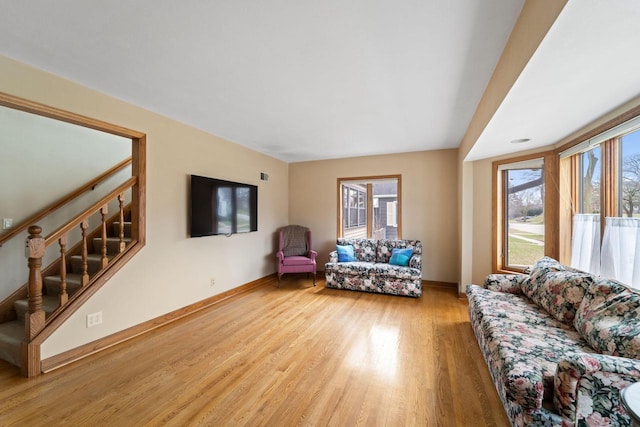 living area featuring a wealth of natural light, stairs, light wood-style floors, and baseboards