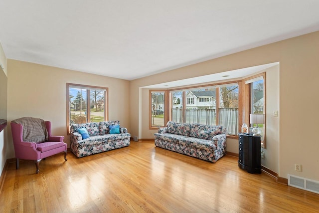 living area featuring visible vents, baseboards, and wood finished floors