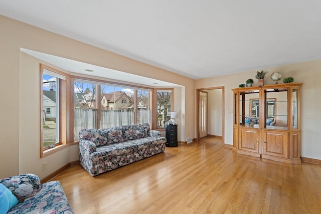 living room with visible vents, baseboards, and light wood-type flooring