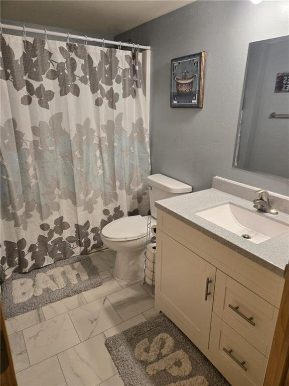 E8577 N County Rd, Elk Mound, WI 54739 - full bathroom featuring vanity, marble finish floor, a shower with curtain, and toilet