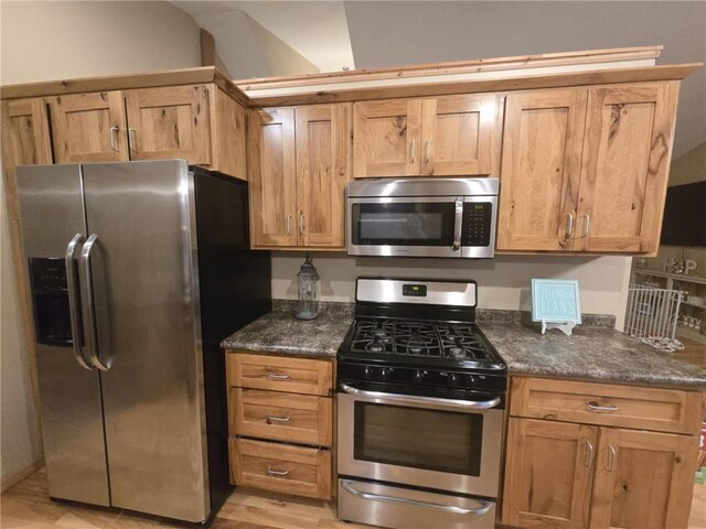 E8577 N County Rd, Elk Mound, WI 54739 - kitchen featuring dark stone countertops, light wood-style flooring, and appliances with stainless steel finishes