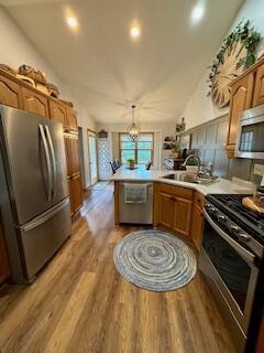 1330 Harvest Cir, Holmen, WI 54636 - kitchen with appliances with stainless steel finishes, a peninsula, a sink, light wood finished floors, and light countertops