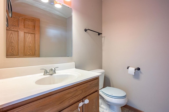 bathroom with toilet, vanity, and baseboards