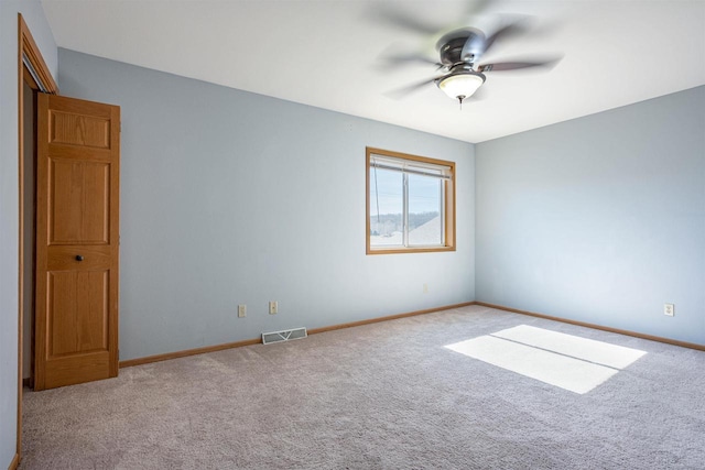 spare room with carpet flooring, visible vents, baseboards, and a ceiling fan