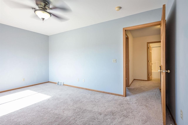 carpeted empty room featuring baseboards, a ceiling fan, and visible vents