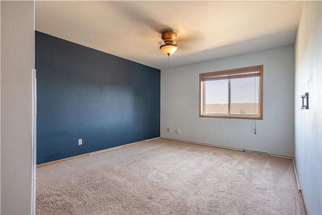 spare room with visible vents, ceiling fan, carpet flooring, and baseboards