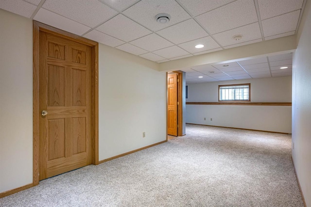basement featuring carpet flooring, baseboards, and a drop ceiling
