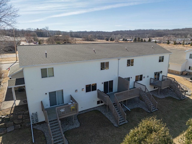 back of house featuring a lawn, stairs, a deck, and a shingled roof