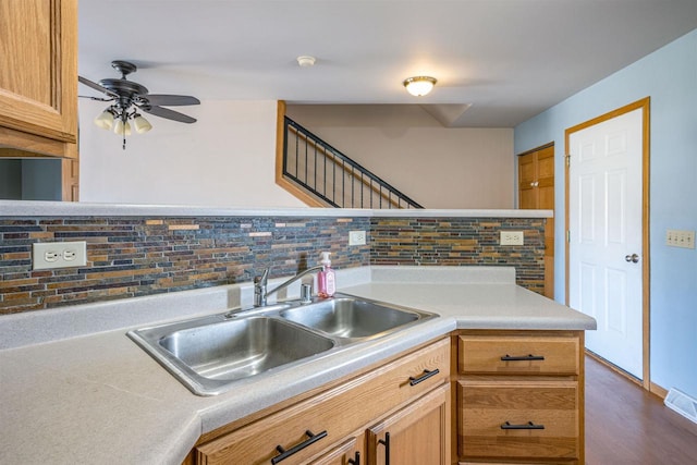 kitchen with dark wood-style floors, light countertops, a ceiling fan, backsplash, and a sink