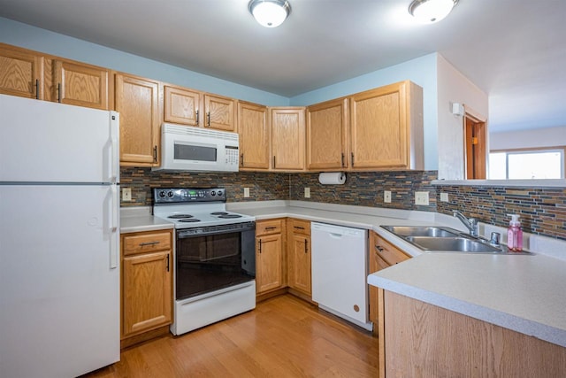 kitchen with light wood-type flooring, white appliances, light countertops, backsplash, and a sink
