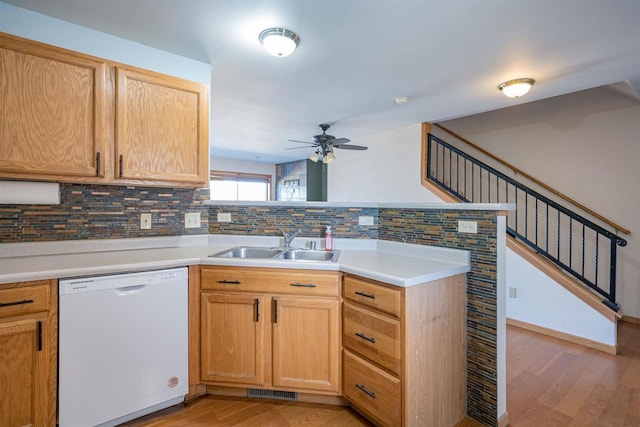 kitchen with light wood-style floors, tasteful backsplash, a peninsula, a sink, and white dishwasher
