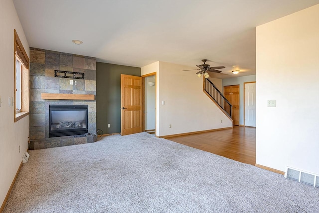 unfurnished living room featuring baseboards, visible vents, a tiled fireplace, and carpet