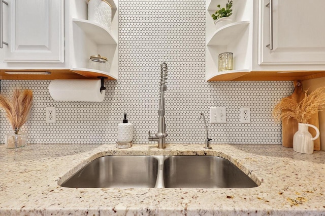 kitchen featuring light stone counters, open shelves, a sink, and tasteful backsplash